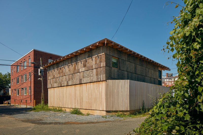Side elevation with glazed upper level and timber base against neighboring brick buildings