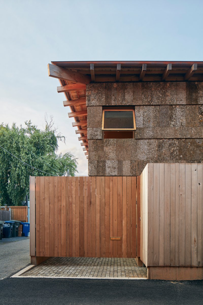 Corner detail of the cantilevered rafters above straw panel wall and timber gate enclosure