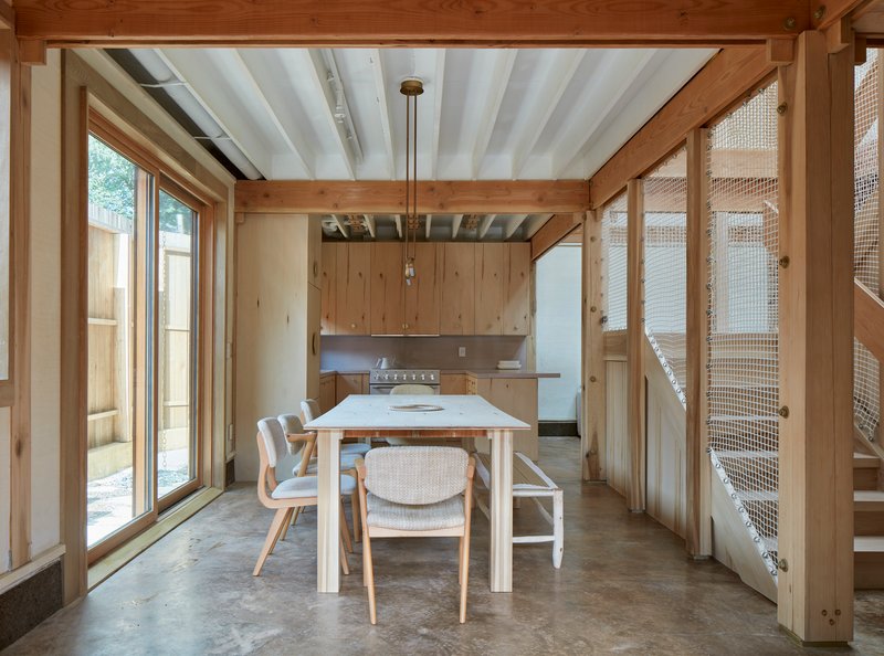 Dining area with exposed timber frame, painted ceiling beams and mesh-panel stair enclosure