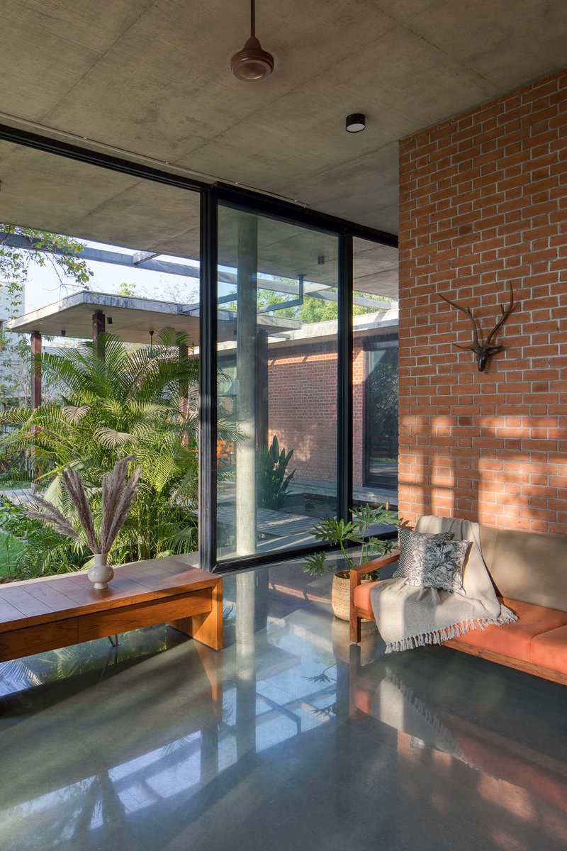 Interior living space with polished concrete floor reflecting light from glazed walls overlooking planted courtyard