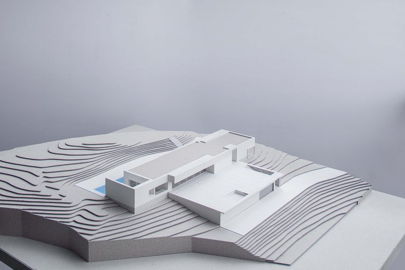 Physical model showing terraced site contours surrounding a flat-roofed residence with pool courtyard