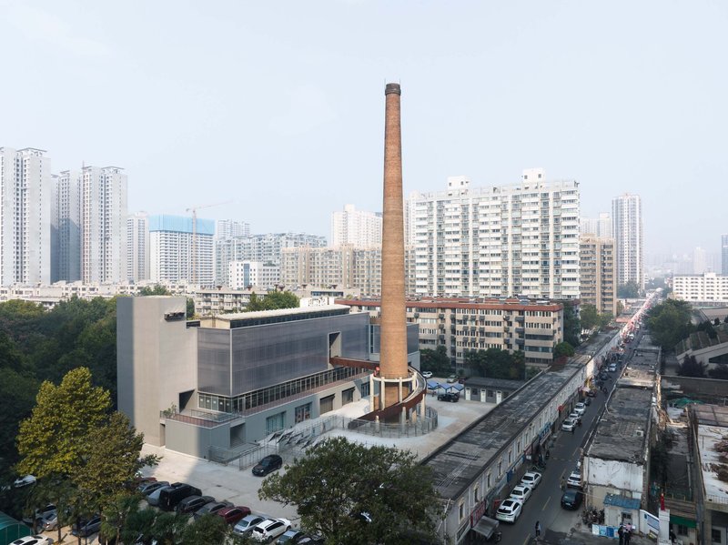 Aerial view of the converted industrial complex with brick smokestack amid surrounding residential towers