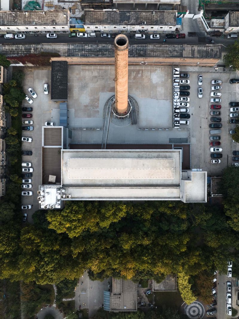 Drone view of the flat roof with circular chimney base and parked cars along adjacent streets
