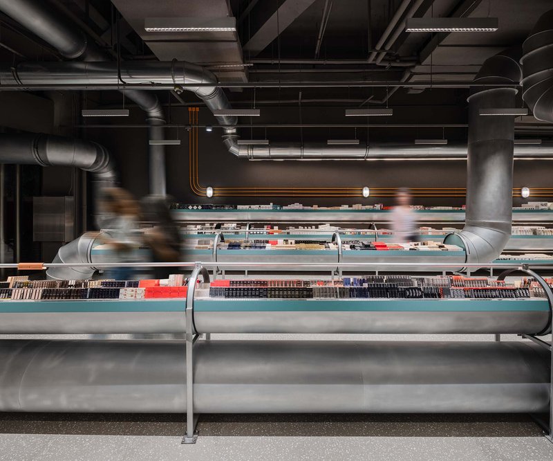 This architectural image showcases a modern retail space with a strong industrial aesthetic. The design features exposed ductwork and metal pipes running across