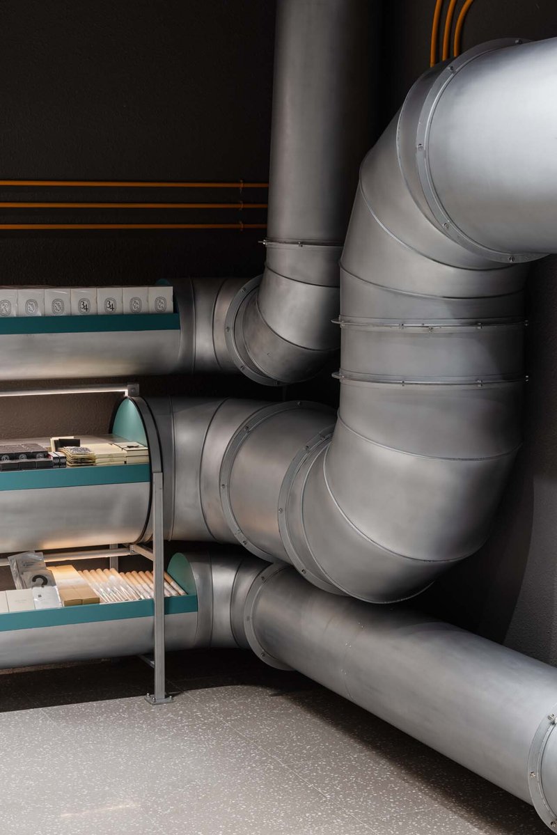 Close-up of curved metal ventilation ducts converging against a black painted ceiling
