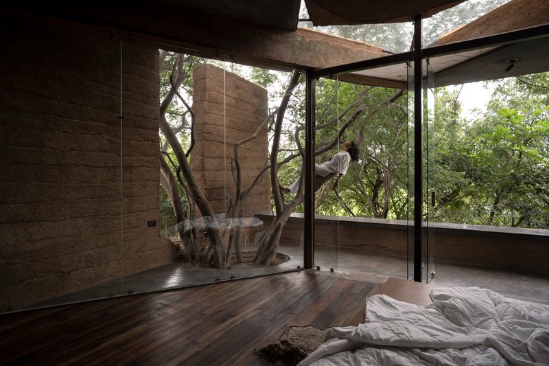 Bedroom with preserved tree trunk penetrating through timber floor and glass enclosure