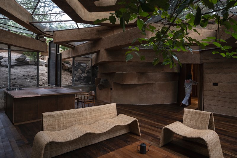 Stepped concrete wall wrapping the interior with exposed roof beams and partial glass ceiling