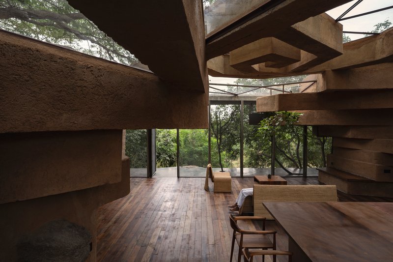 Double-height living area framed by horizontal concrete beams and full-height glazed walls