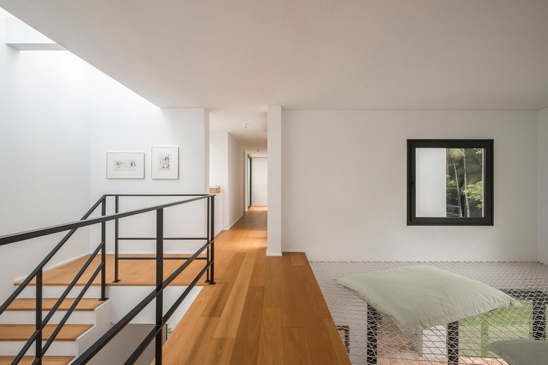 Upper corridor with timber flooring, steel railing overlooking mesh screen, and framed window