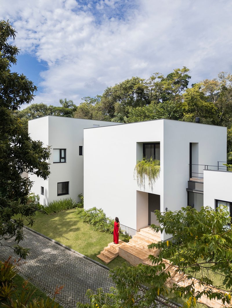 Elevated white facade with recessed entrance and figure in red descending brick steps to lawn