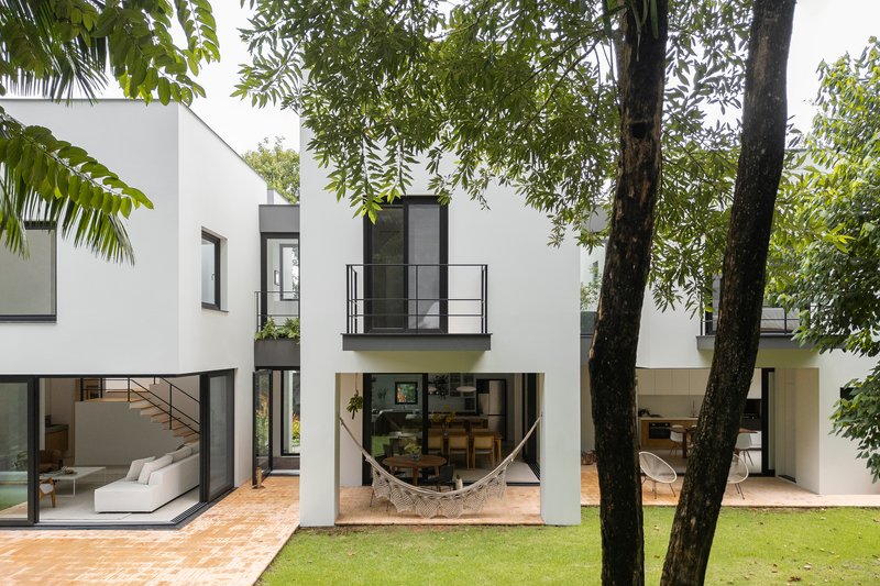 Rear elevation with glazed openings and hammock on terrace between tree trunks and lawn