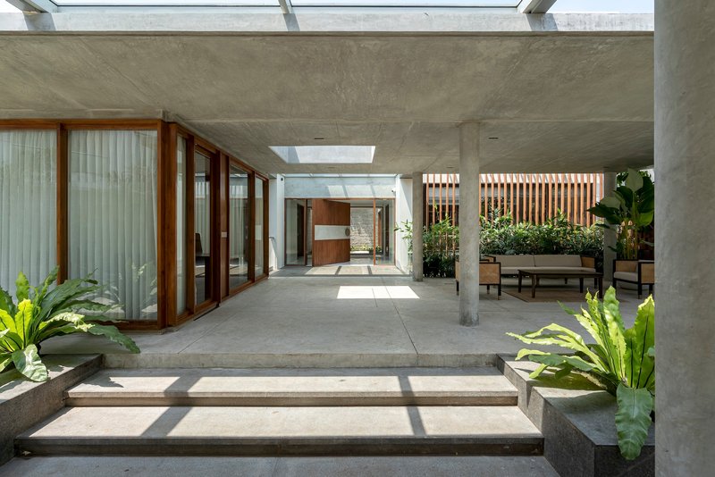 Interior courtyard with concrete steps, timber-framed glazing, and planted beds under skylights