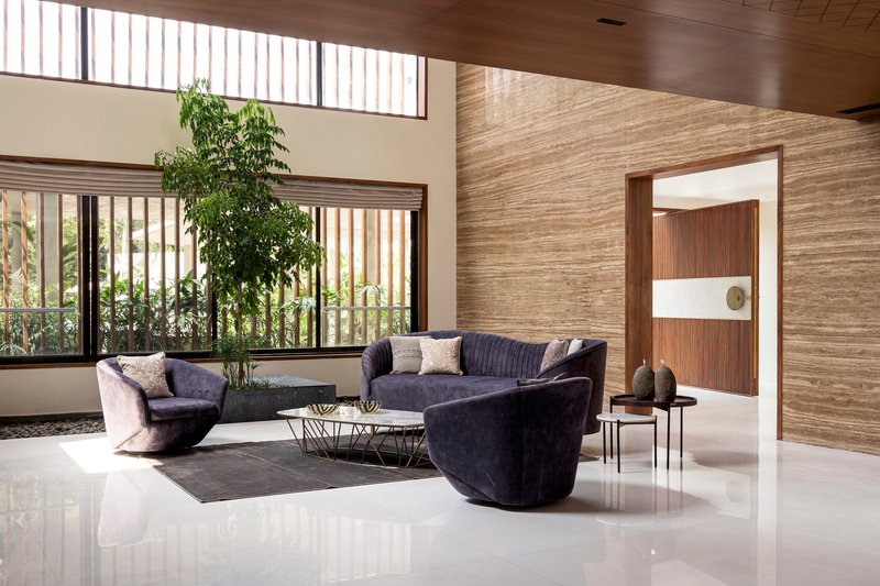 Living room with clerestory windows, horizontal stone wall cladding, and view to planted courtyard