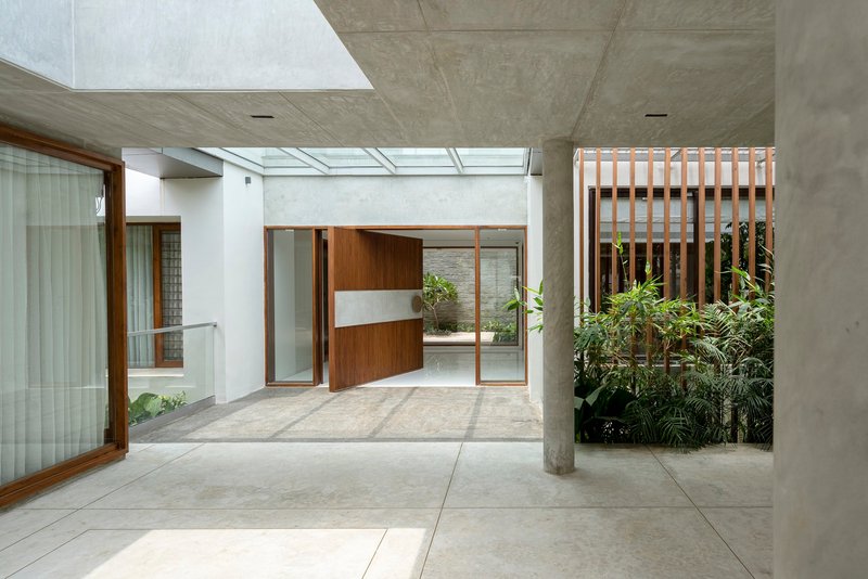 Concrete portico with cylindrical column framing the timber pivot door and skylights above the entrance