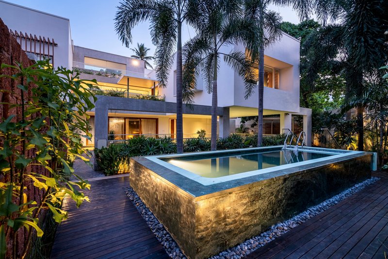 Elevated lap pool with textured stone base and underwater lighting surrounded by timber deck and palms at twilight