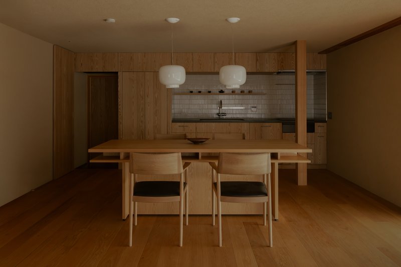Dining area with timber table, chairs, and wood cabinetry beneath pendant lights