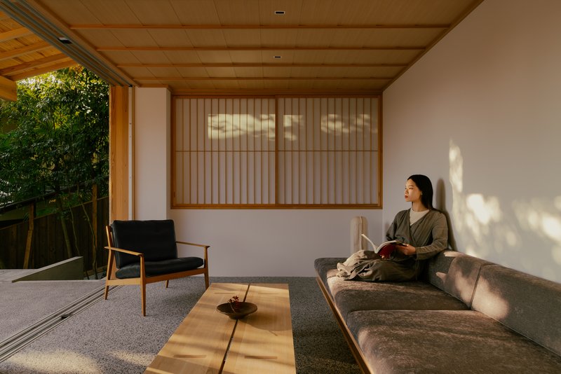 Covered terrace with person reading on curved bench beneath dappled afternoon light