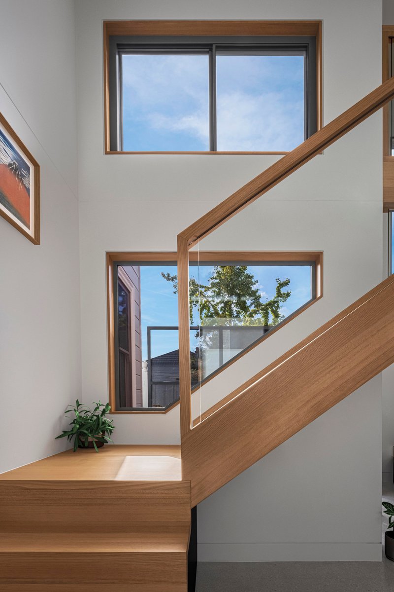 Staircase landing with timber-framed windows framing views of neighboring rooftops and trees