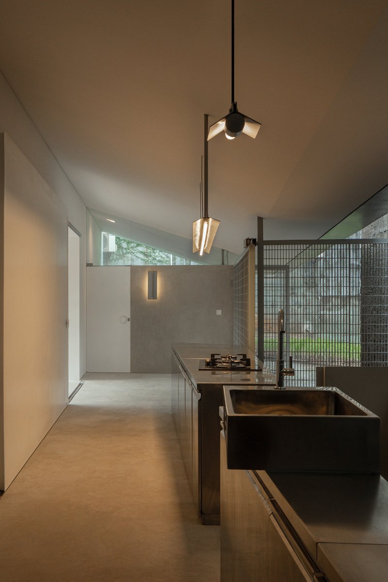 Kitchen island with dark steel sink and pendant lights suspended from the angled ceiling
