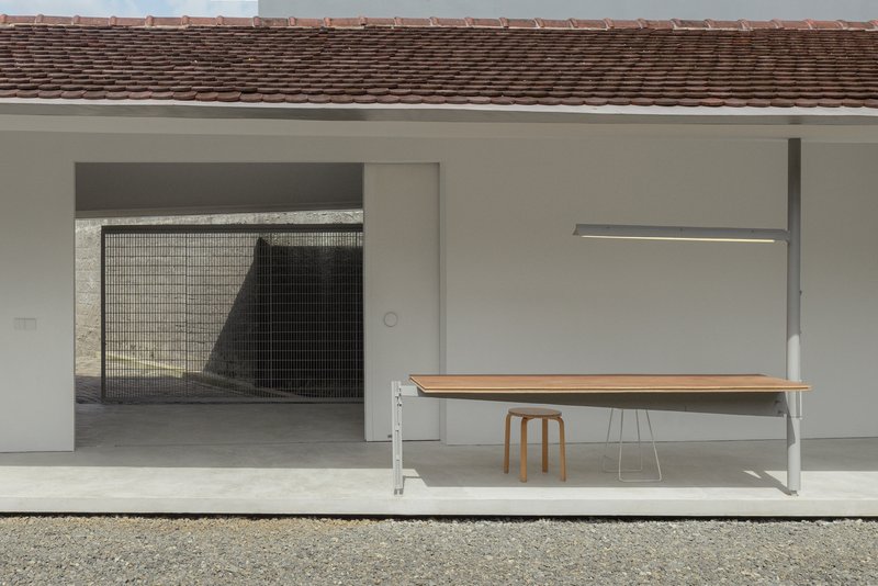 Covered terrace with a wooden bench and mesh screen opening beneath a tiled roof overhang