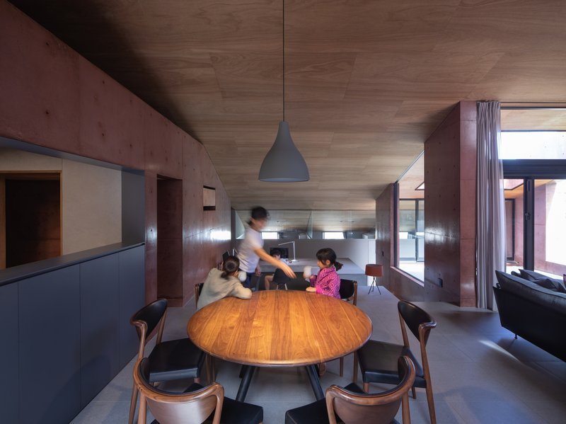 Dining area with round timber table where a family gathers beneath a pendant light