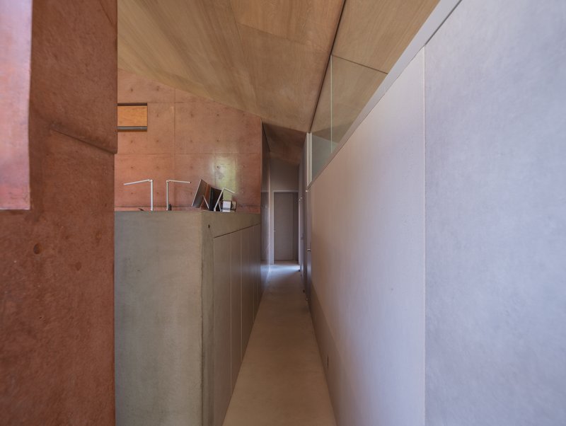 Corridor with timber ceiling, exposed concrete walls, and white millwork beneath a clerestory window