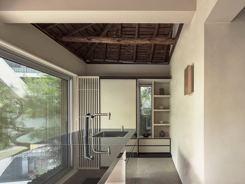 Bathroom with stone sink and vertical timber screen beneath reclaimed wooden ceiling beams