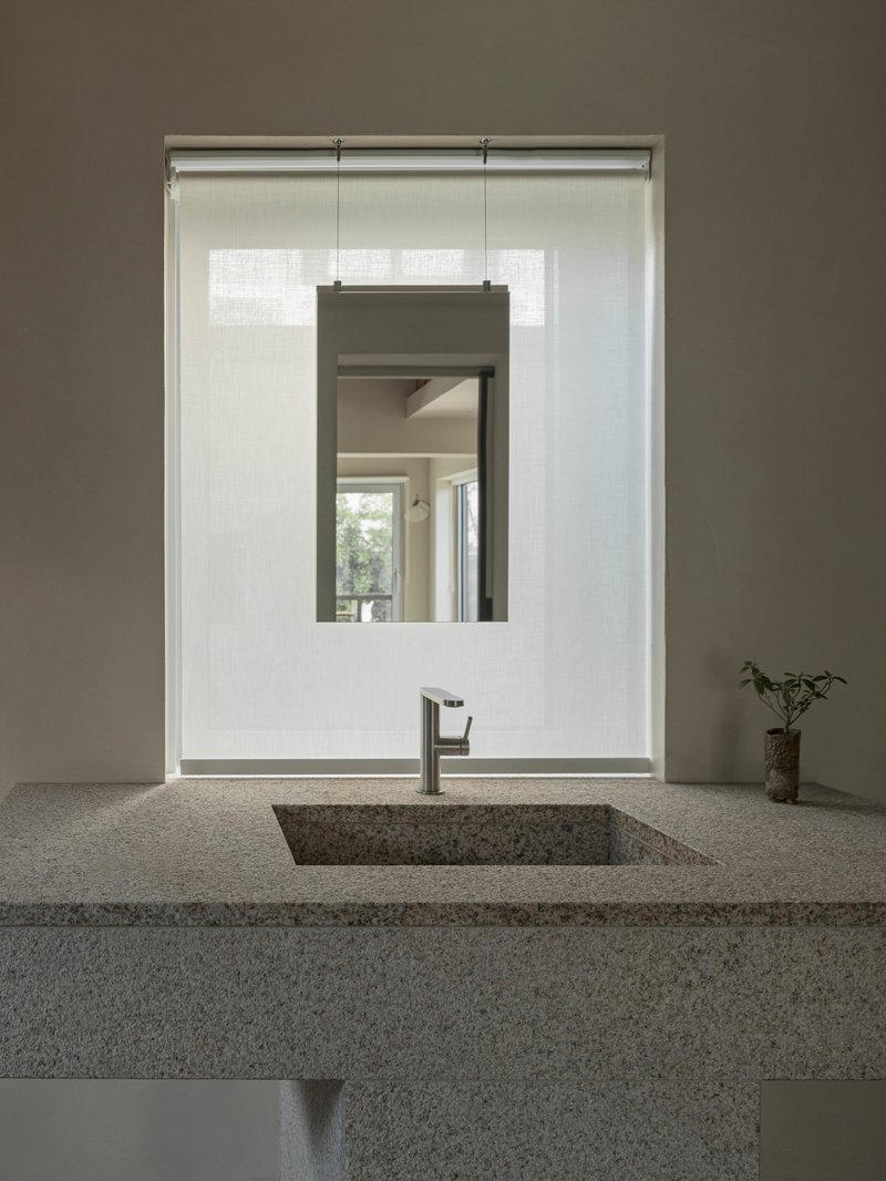 Terrazzo vanity counter with rectangular basin and suspended mirror framed by white tile