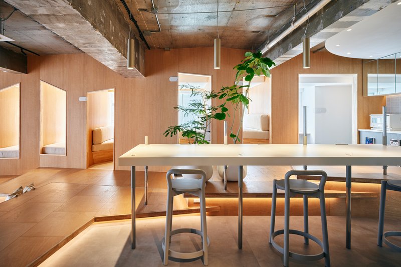 Plywood dining table with pendant lights and arched openings framing sleeping alcoves beyond