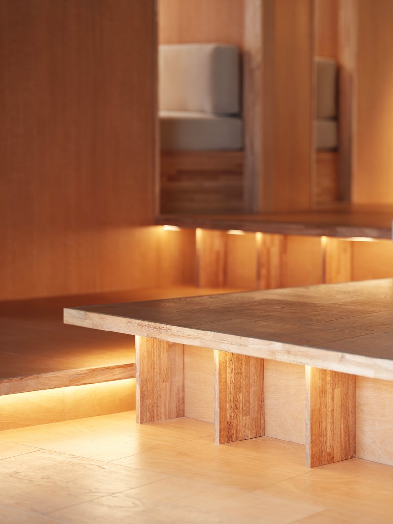 Low table with timber legs and integrated strip lighting beneath wood cabinetry with recessed cove illumination