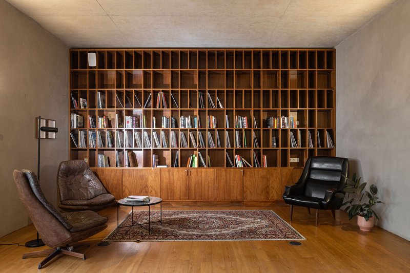 Library room with floor-to-ceiling timber shelving, two leather chairs and a patterned rug