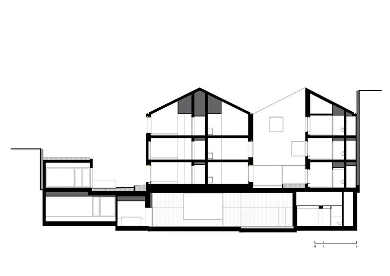 Section drawing revealing multi-story residential volumes with pitched roofs and a shared basement level