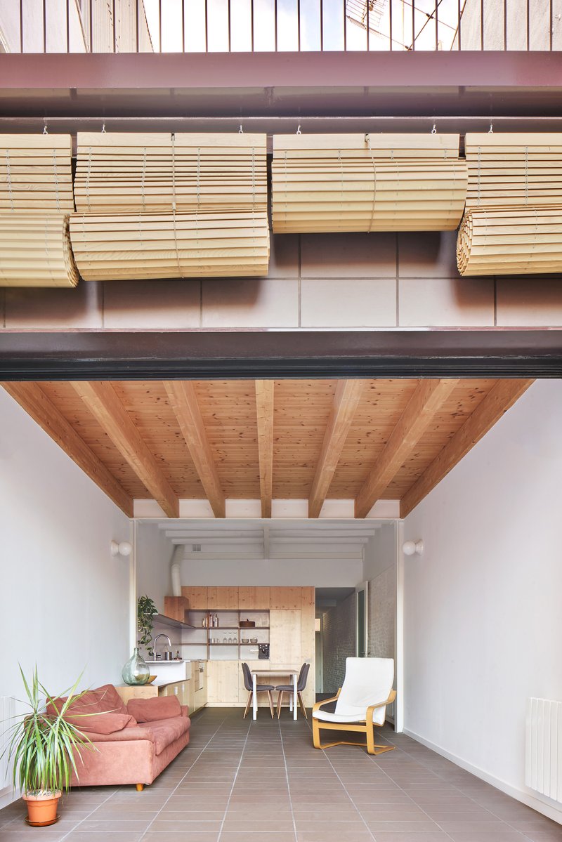 Double-height space with exposed timber ceiling joists, mezzanine level and timber venetian blinds