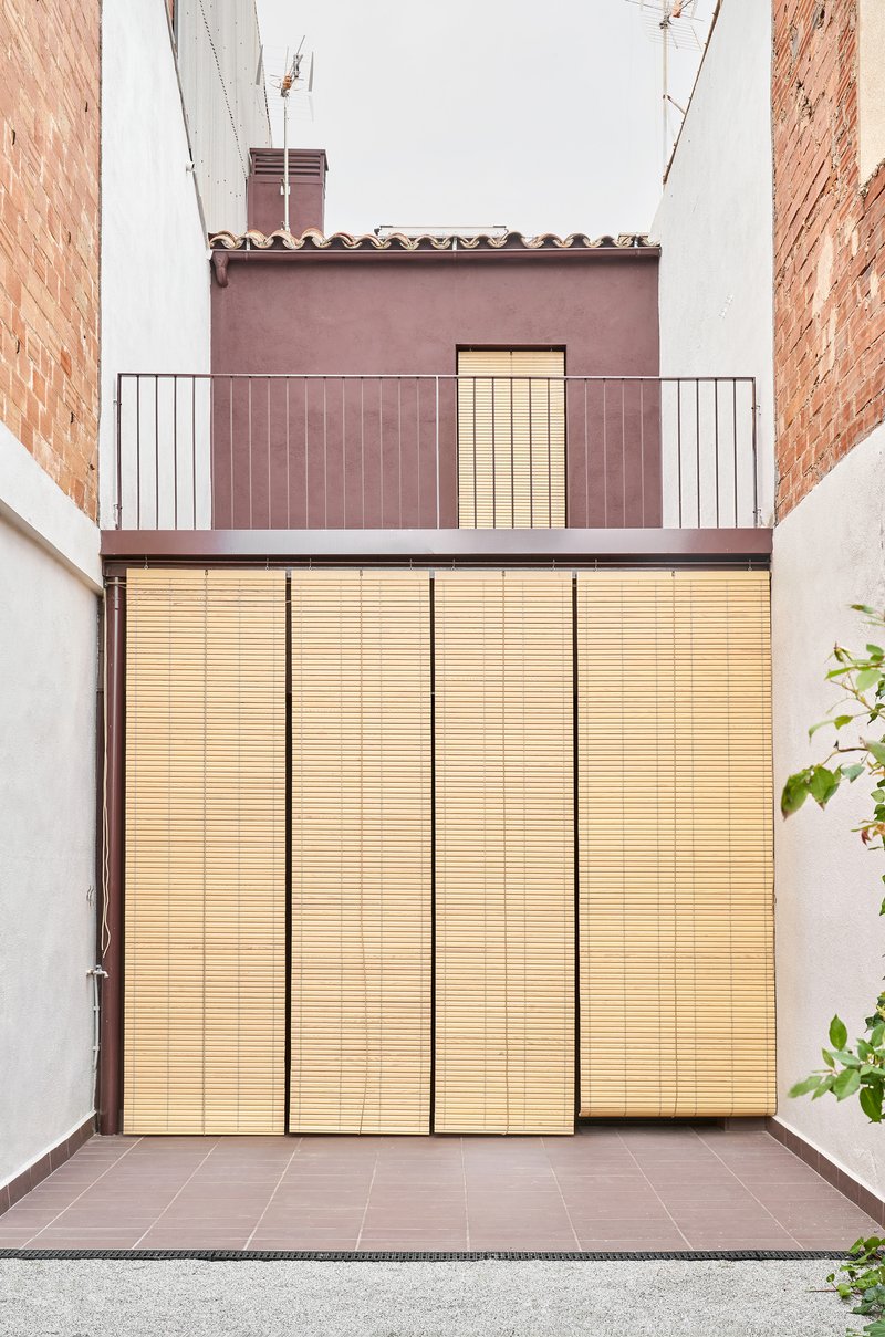 Rear facade with retractable timber slatted shutters fully closed over glazed openings between brick party walls