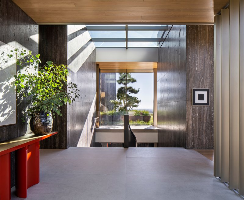 Entry foyer with board-formed concrete walls and clerestory opening casting diagonal shadows on the floor