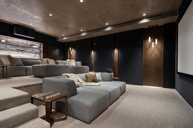 Screening room with tiered seating facing a projection wall under a textured concrete ceiling