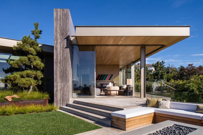 Glazed pavilion with cantilevered roof and stepped timber deck beside a sunken garden bed