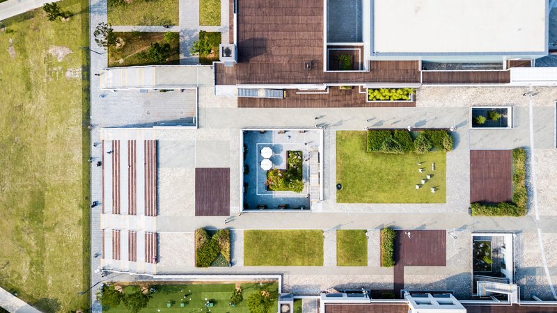 Aerial view of the concrete courtyard with planted roof terraces and timber-clad volumes