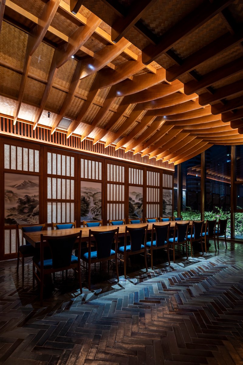 Dining hall with curved timber beam ceiling and translucent shoji screens along one wall at night
