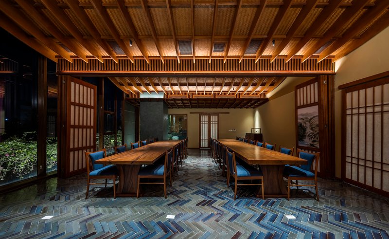 Dining room with herringbone tile floor and exposed timber coffered ceiling opening to a planted courtyard
