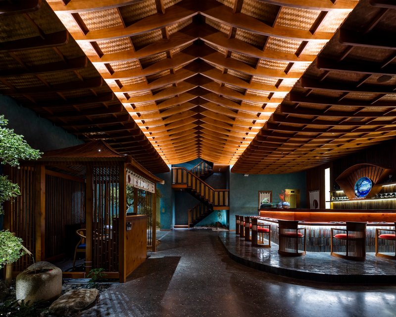 Double-height lobby showing the vaulted wood-slat ceiling with integrated lighting above a central interior garden