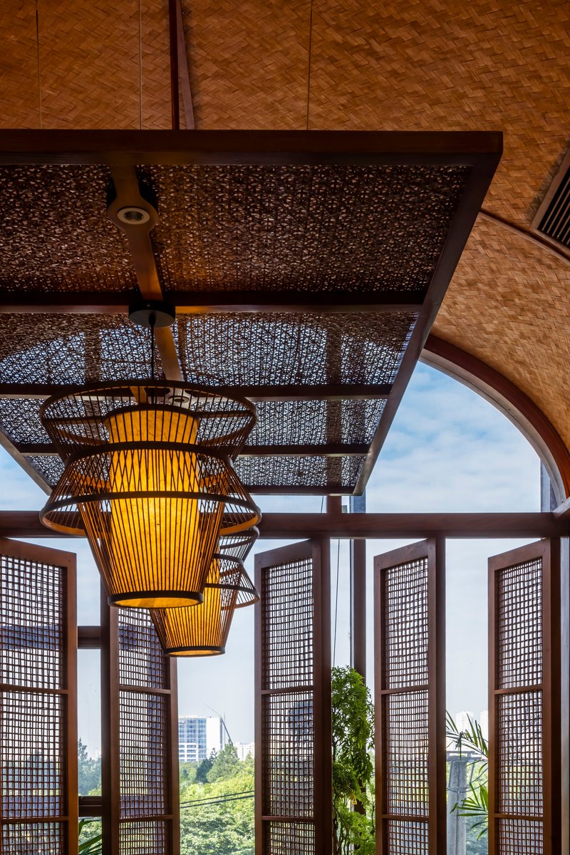 Woven bamboo pendant lights suspended below a latticed ceiling screen and arched timber-framed windows