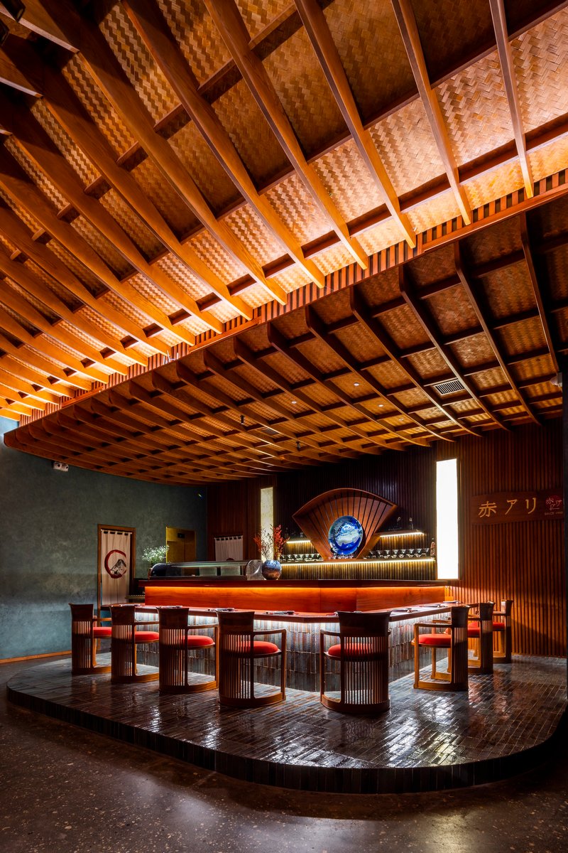 Dining area with woven bamboo coffered ceiling above circular platform and timber counter with stools