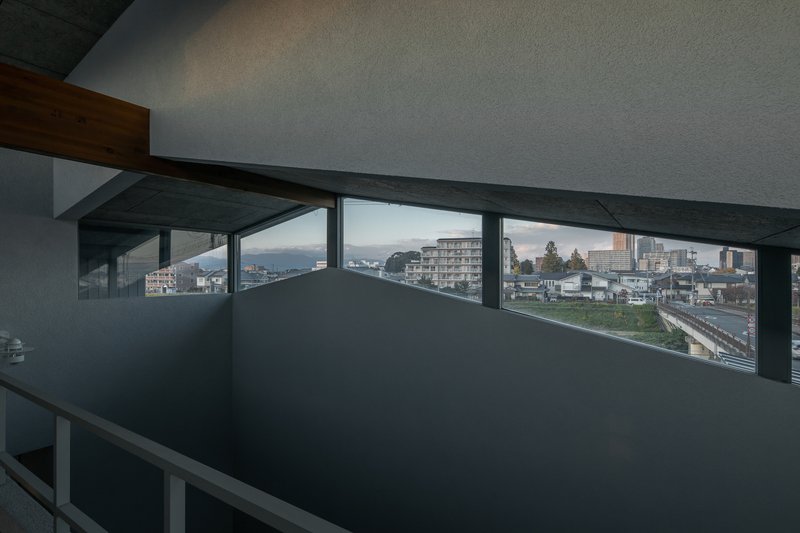 Upper-level interior corridor with horizontal band windows framing distant mountains and residential neighborhood at dusk