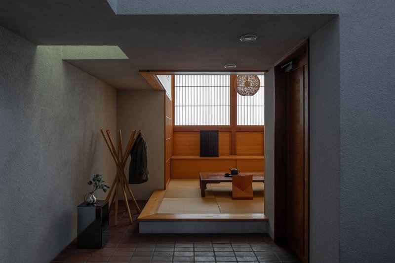 View from entry vestibule through open doorway into tatami room with low table and pendant light