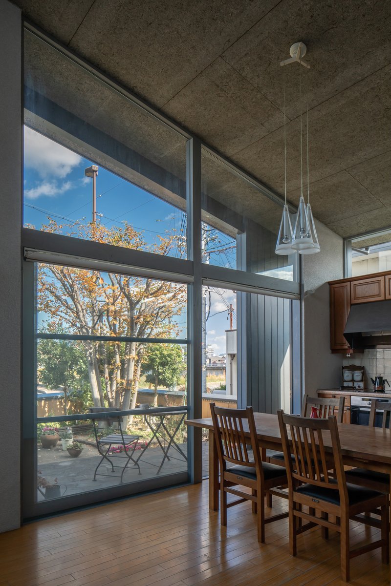 Dining area with floor-to-ceiling glazing framing an autumn tree and outdoor terrace beyond