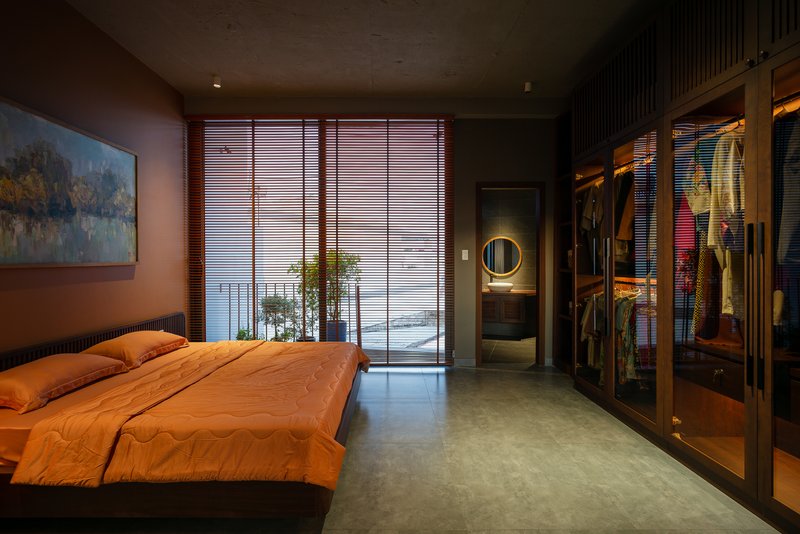 Bedroom view toward open closet and adjoining bathroom with circular mirror at twilight