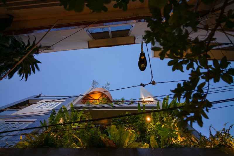 Upward view from below showing the arched roof form and planted balconies at dusk
