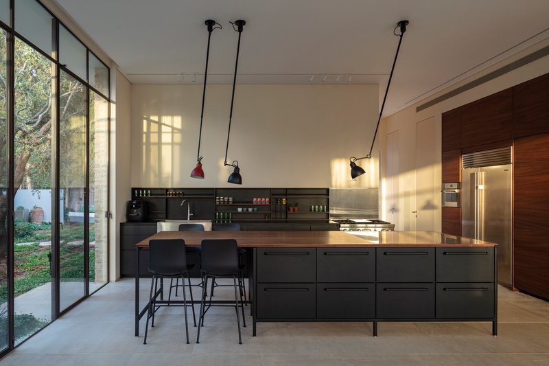 Kitchen island with timber top and pendant lights at dusk with courtyard visible through glazing