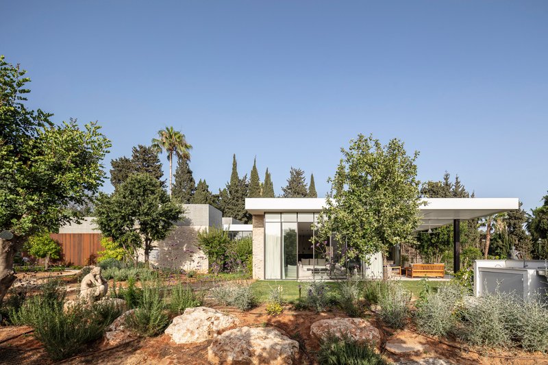 Low-slung pavilions with flat roofs arranged around a planted courtyard with limestone boulders
